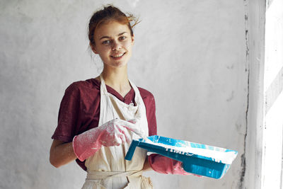 Portrait of young woman standing against wall