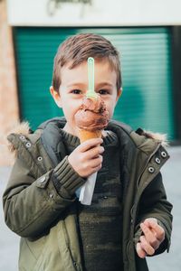 Portrait of boy holding ice cream cone while standing outdoors