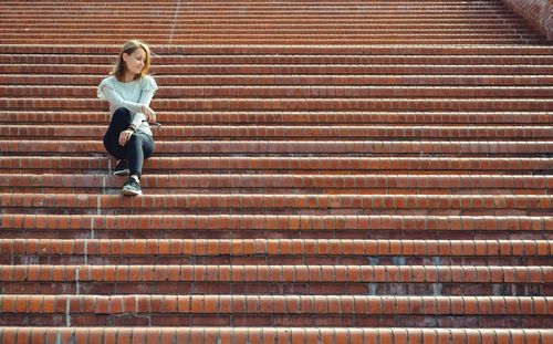 Full length of woman sitting on staircase