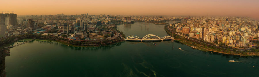 Aerial view of bridge over river and buildings against sky during sunset