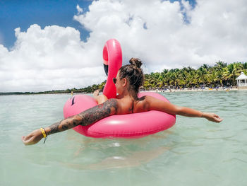 Young woman relaxing on pool raft in sea during vacation