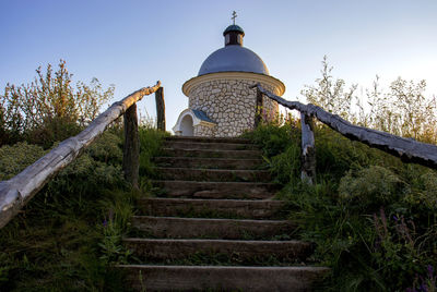 Low angle view of steps amidst trees and building against sky
