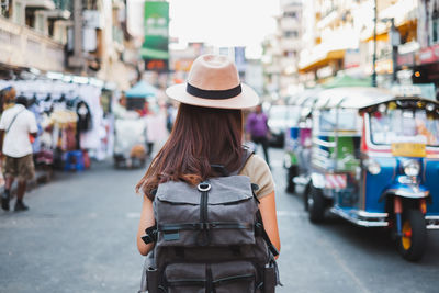 Rear view of woman standing on street in city