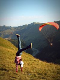 Woman doing handstand on field against sky