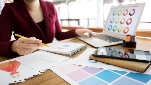 Midsection of woman holding paper with text on table