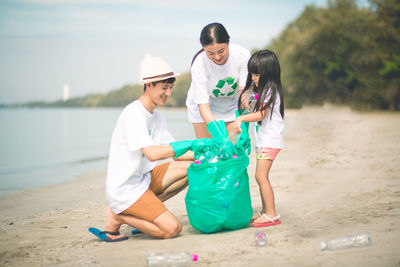 Parents with daughter collecting plastic at beach