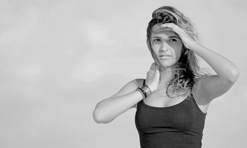 Young woman shielding eyes against clear sky