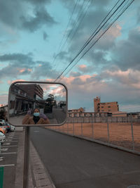 Road by city against sky during sunset