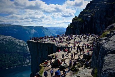 People on preikestolen against cloudy sky during sunny day