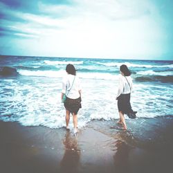 Rear view of women on beach against sky