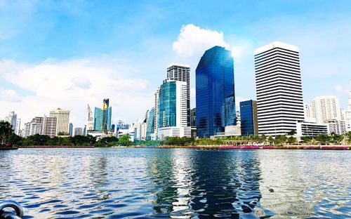 Modern buildings by river against sky in city