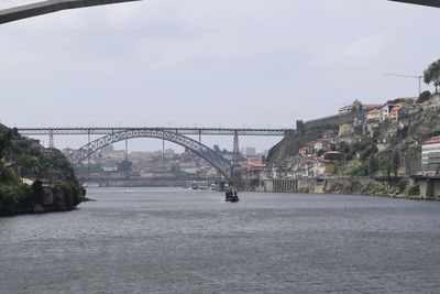 Bridge over river in city against sky