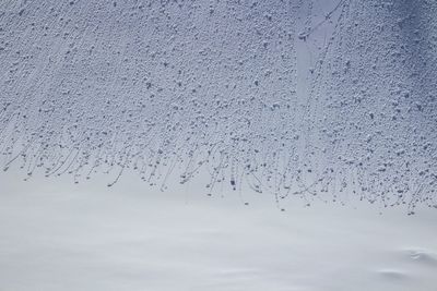 Close-up of snow covered glass against sky