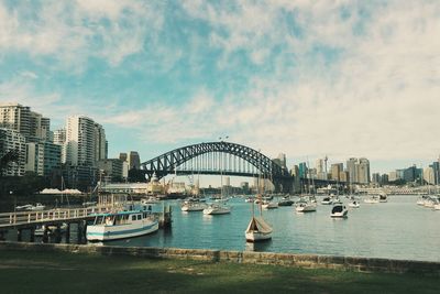 Boats in river against cloudy sky