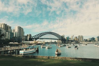 Boats in harbor against cloudy sky