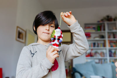 Low angle view of child holding in hands santa claus toy decoration for christmas tree