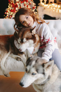 Close up of cute girl hugging husky dog on christmas background