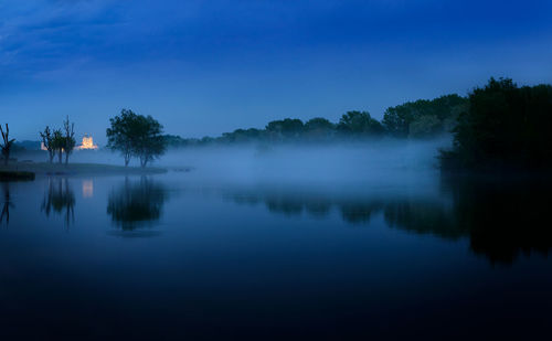 Reflection of trees in lake against blue sky