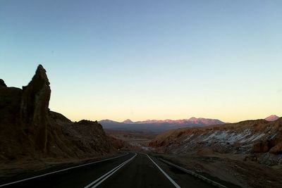 Road by mountains against clear sky