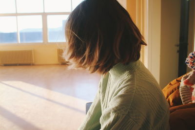 Side view of woman sitting at home