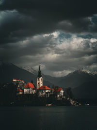 Illuminated buildings by river against sky at night