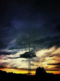 Low angle view of electricity pylon against cloudy sky