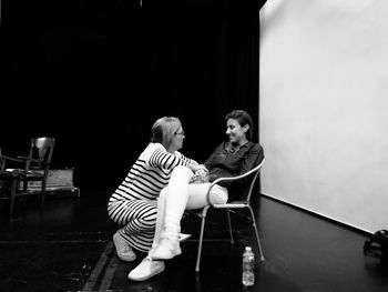 Rear view of two women sitting on floor