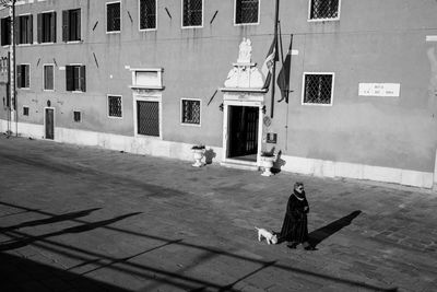 High angle view of woman with dog walking on footpath against building in city