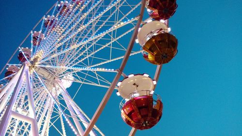 Low angle view of ferris wheel against clear blue sky