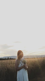 Rear view of woman standing on field against clear sky