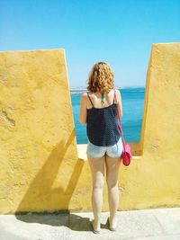 Full length of woman standing against blue sky