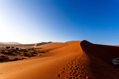 Scenic view of desert against clear blue sky