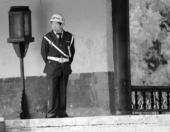 Full length of man wearing uniform while standing against wall