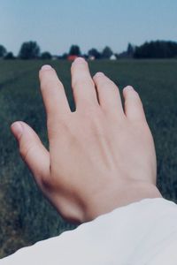 Cropped hand of woman over field