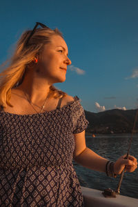 Close-up of young woman standing in sea against sky