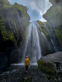 Rear view of man standing against waterfall