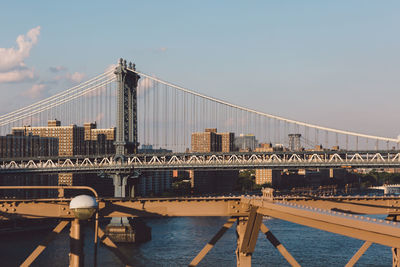 Suspension bridge in city against clear sky