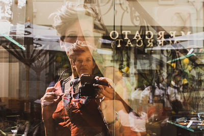 Reflection of man photographing on glass