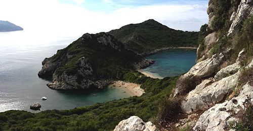 Scenic view of sea by mountains against sky