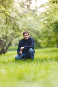 Portrait of smiling man crouching on field