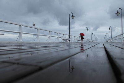 Person walking on railing against sky