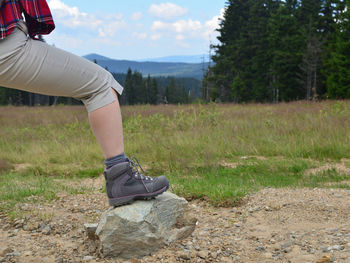 Female leg in tracking shoe resting on a stone in mountain