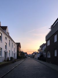 Street amidst buildings against sky during sunset