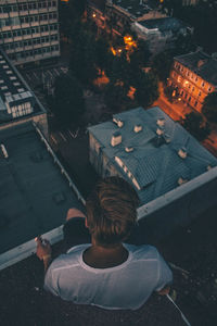 High angle view of man sitting on terrace in city at dusk