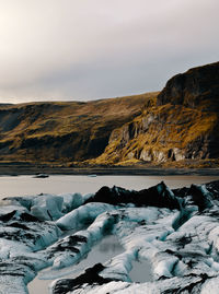 Scenic view of sea by mountains against sky during winter