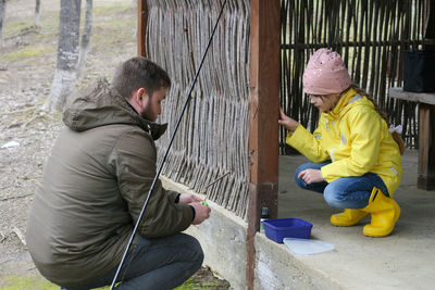 Dad shows his daughter how to put the bait on the hook of the fishing rod