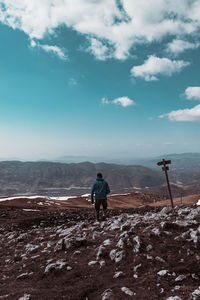 Rear view of man walking on mountain against blue sky