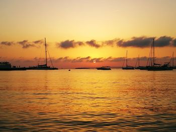 Sailboats sailing in sea against sky during sunset