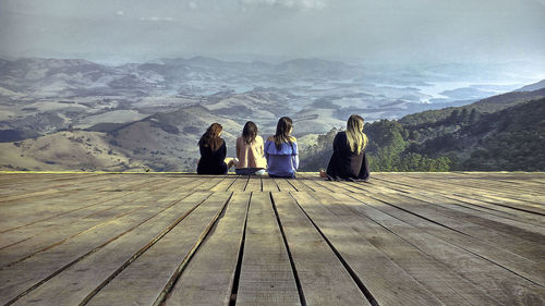 Rear view of friends standing on mountain against sky