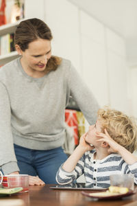 Mother and son talking at dining table in living room